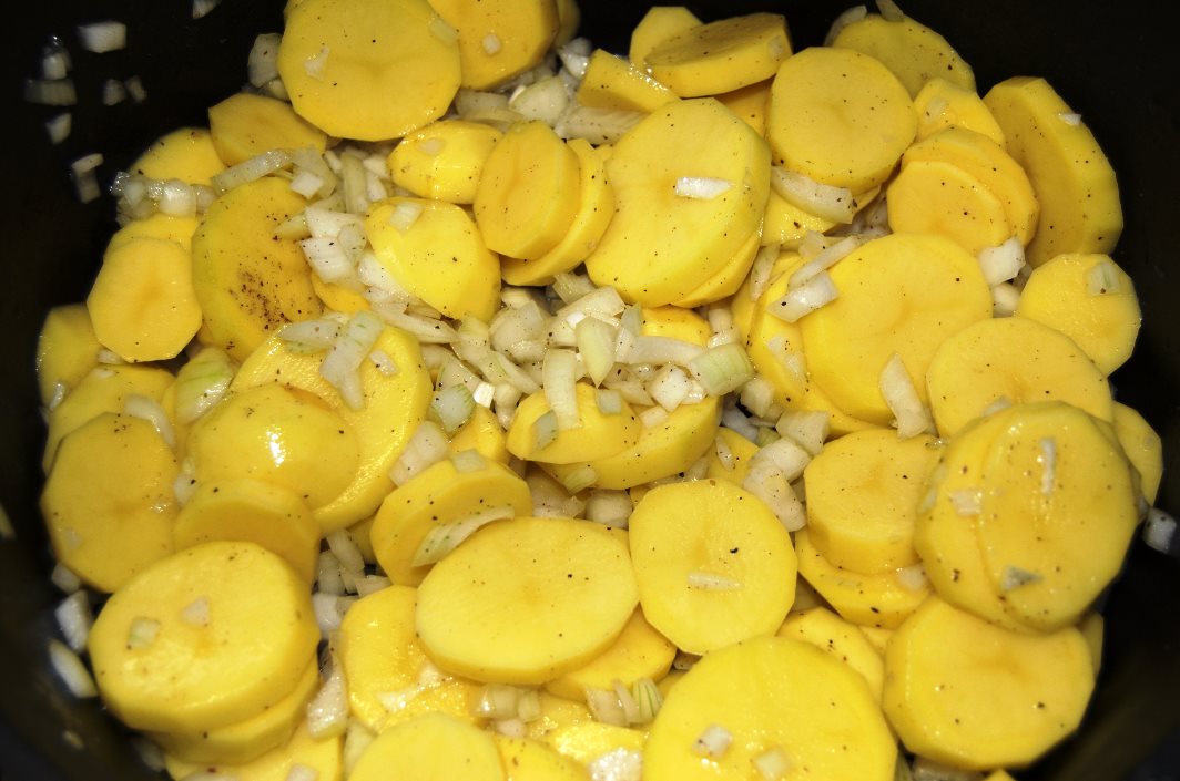 Kartoffeln schälen, in Scheiben schneiden, Zwiebeln dazu und würzen